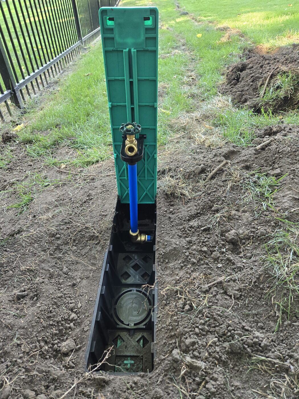 Pop-up spigot water box open with brass hose faucet raised on a blue riser for hose hookup