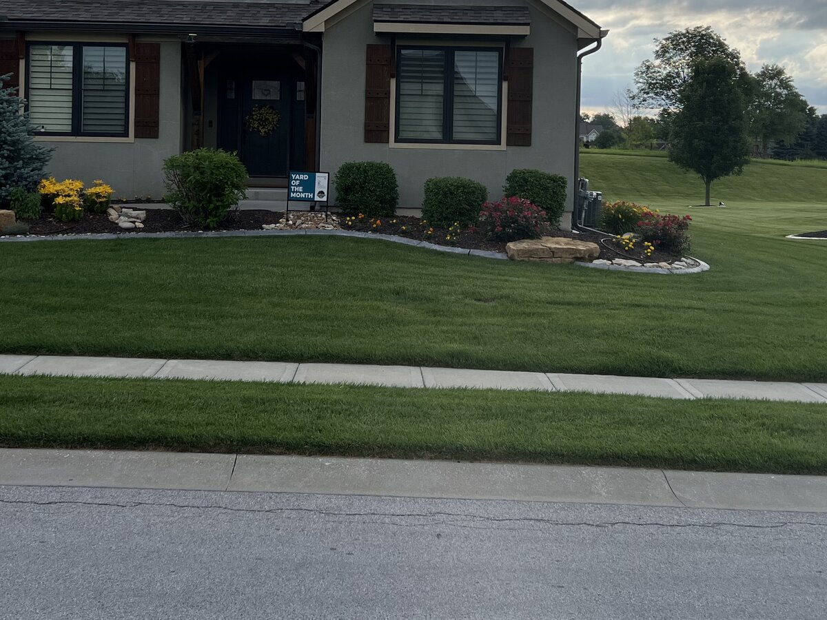 Yard of the Month winner - beautiful residential lawn and landscape with the sign prominently displayed in the front yard